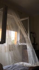 a window with a white curtain on top of a bed at aLO MARRAKECH in Kasba Aït Youdi