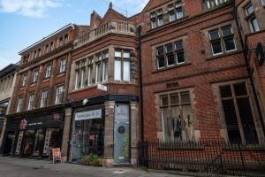 a brick building on a city street with a store at Deluxe 2 Bedroom Apartment In City Centre in Nottingham