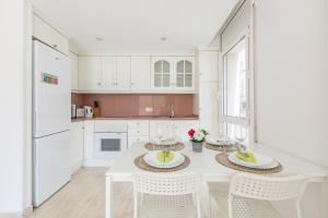 a white kitchen with a white table and chairs at Nova Apartment by Hello Homes Sitges in Sitges