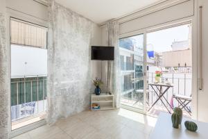 a living room with large windows and a flat screen tv at Nova Apartment by Hello Homes Sitges in Sitges