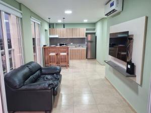 a living room with a leather couch and a kitchen at Fenix 4 Alquiler Temporario in Formosa
