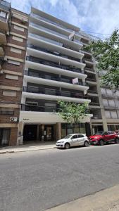 a large building with cars parked in front of it at Monumento y Río - Parking privado con costo adicional in Rosario