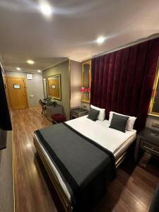 une chambre avec un grand lit avec une tête de lit rouge dans l'établissement Gimat Otel, à Yenimahalle