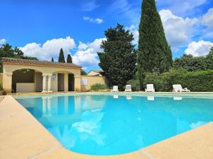 a swimming pool with two white chairs and trees at Domaine de la Source, Charme & piscine à Uzès in Uzès