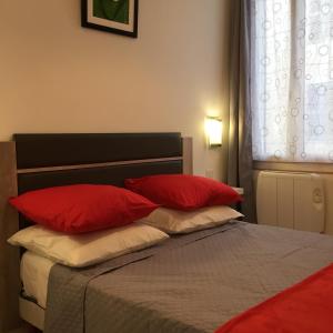 a bedroom with a bed with red pillows and a window at Appartement Le Vieux Port in Marseille