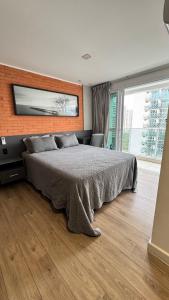 una camera da letto con un letto grande e un muro di mattoni di Flat Barra - Rio Centro a Rio de Janeiro