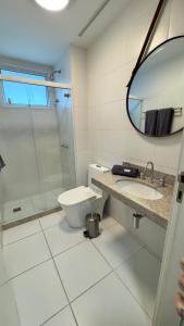 un bagno con un water, un lavandino e uno specchio di Flat Barra - Rio Centro a Rio de Janeiro