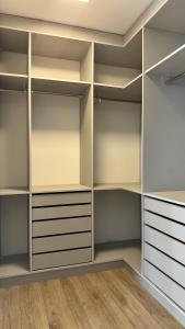 una cabina armadio con ripiani bianchi e pavimenti in legno di Flat Barra - Rio Centro a Rio de Janeiro