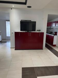 a kitchen with red cabinets and a flat screen tv at Belle chambre à louer in Argenteuil +5 photos