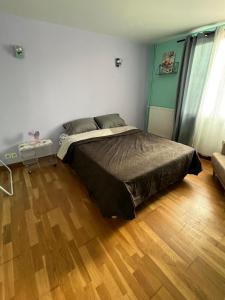 a bedroom with a bed and a wooden floor at Belle chambre à louer in Argenteuil