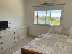 a bedroom with a bed with a dresser and a window at Casa en barrio privado en Escobar, laguna y pileta in Belén de Escobar +12 photos