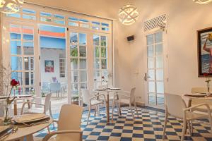 ein Restaurant mit Tischen, Stühlen und Fenstern in der Unterkunft Placita Vieja Hotel Boutique Spa in Santa Marta