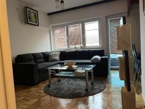 a living room with a black couch and a table at Apartman Aylin in Tuzla