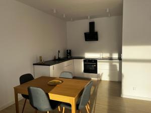 a dining room with a table and chairs and a kitchen at Apartamenty pod sosną in Zakrzewo