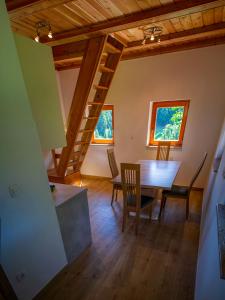 a dining room with a table and chairs and two windows at Wooden Chalet - Homestead Vrhovc in Železniki