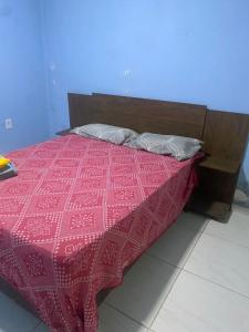 a bed with a red bedspread and a wooden headboard at Casa grande in Garanhuns