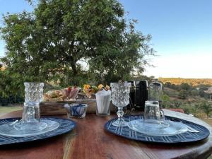 a wooden table with two plates and glasses on it at Chalé Village Jângal in Machado