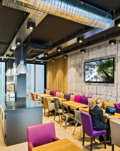 un restaurant avec des tables et des chaises et une personne assise à une table dans l'établissement Campanile Rennes Centre - Gare, à Rennes