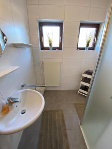 a bathroom with a sink and a shower and two windows at Gemütliche EG-Ferienwohnung Brazil mit eingezäunten Garten in Aurich