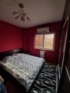 a red bedroom with a bed and a window at Apartman Aylin in Tuzla