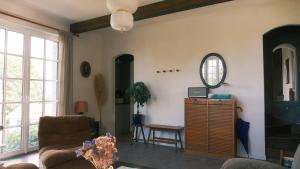 ein Wohnzimmer mit einer Couch und einem Spiegel in der Unterkunft Maison Maa, Maison de gardien, à 10 min à pieds de St Valery sur somme le long du canal in Boismont