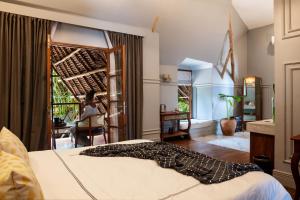 a bedroom with a bed and a woman sitting in a chair at Upendo Beach Boutique Hotel Zanzibar in Michamvi