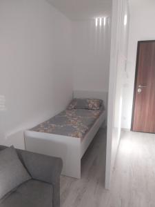 a small bedroom with a bed and a chair at Stan na dan in Žepče