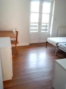 biały pokój z drewnianą podłogą i dwoma oknami w obiekcie Maison charmante à Sainte-Agnés w mieście Sainte-Agnès