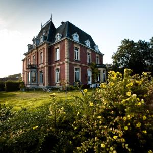 una casa vieja en un campo de hierba con flores en Chateau Neufays en Theux