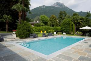 a swimming pool with chairs and mountains in the background at Villa Confalonieri in Mandello del Lario