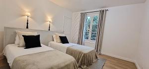 two beds in a room with a window at Le Patio de l'Isle in Périgueux