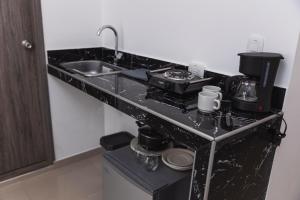 a kitchen with a black counter top with a sink at Hotel Boutique Business Center in Cali