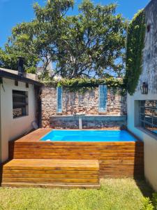 a swimming pool with a wooden deck next to a building at Lechuza del Campanario in San Antonio de Areco