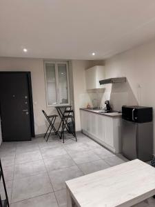 a kitchen with white cabinets and a black refrigerator at Studio en centre ville in Montceau-les-Mines