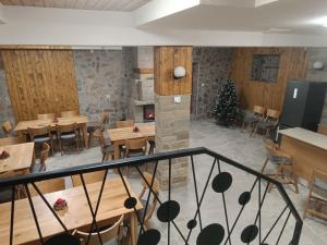 a restaurant with wooden tables and chairs and a christmas tree at Червената къща in Perushtitsa