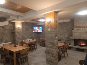 a restaurant with tables and chairs and a fireplace at Червената къща in Perushtitsa