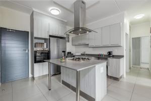 a kitchen with white cabinets and a large island at Fredas Place 92 On New in Midrand