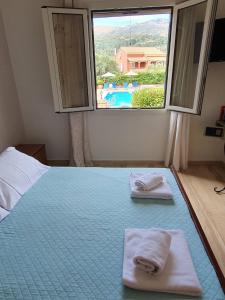 a bedroom with two towels on a bed with a window at Emily's Apartments in Kassiopi