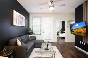 sala de estar con sofá gris y TV de pantalla plana en Relaxing 1BR w Pool-Parking, Near Rvrwlk-Conv Ctr, en San Antonio