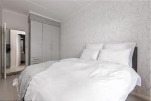 a white bed with white sheets and pillows at Fredas Place 92 On New in Midrand +9 photos