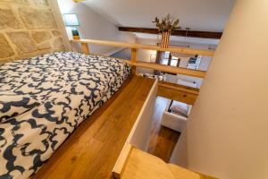 a small bedroom with a bed and a wooden floor at Duplex Caché Toits & Tradition in Sommières