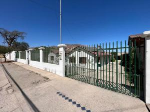 a white fence with a green gate on a street at Hostal Casa 95 in Vicuña