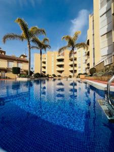 a large swimming pool with palm trees and buildings at Casa Soñada -Appartment with pool and garage in Los Alcázares
