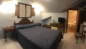 a bedroom with a bed and a desk and a television at Hotel Rural Villa Elena in Panes