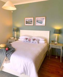 a bedroom with a large white bed with two tables at Cape Town cottage near colony of penguins in Simonʼs Town