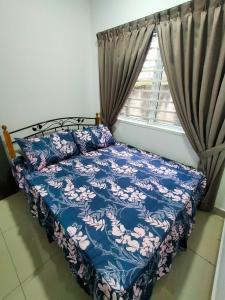 a bedroom with a bed with a blue comforter and a window at Homestay hanamuslim senawang in Seremban