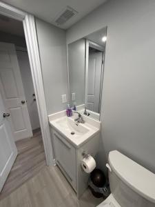 un bagno con lavandino, water e specchio di Ravine Retreat - 3RM Suite, 2BD, 1 WR, Pool, Sauna a Whitby Altre 27 foto