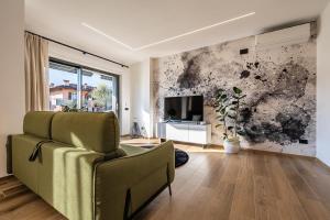 un soggiorno con sedia e TV di ELVY Garda Living Garden a Riva del Garda