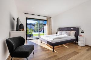 una camera da letto con un letto, una sedia e una finestra di ELVY Garda Living Garden a Riva del Garda