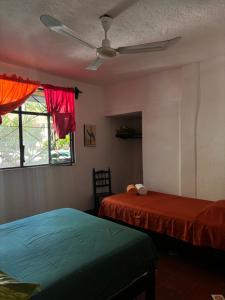 una camera da letto con due letti e un ventilatore a soffitto di Casa Bastin a Puerto Escondido